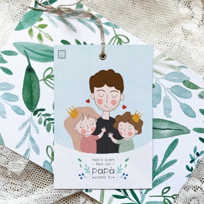 etiqueta com ilustração e texto sobre papel, pendurada em envelope com padrão de folhas verdes em tecido rendado branco