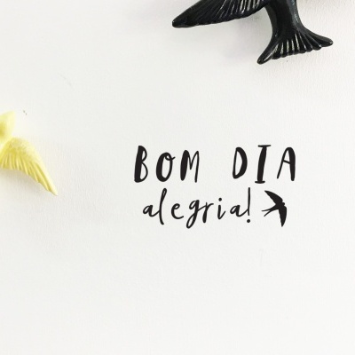 Parede branca com pássaros em relevo e texto 'BOM DIA alegria!'