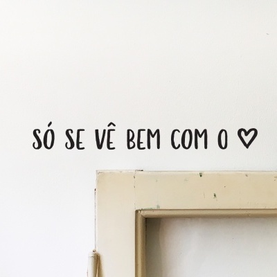 Frase em parede branca acima de moldura creme com cabo verde pendurado