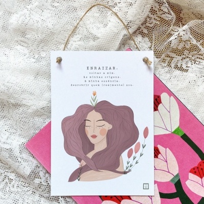 Cartaz ilustrado com texto pendurado sobre tecido de renda branca e tecido rosa com flores.