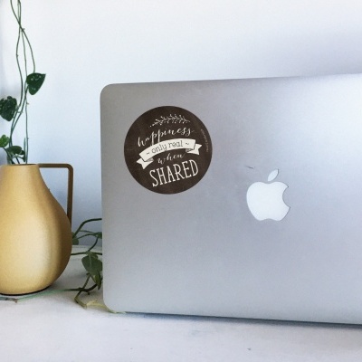 Computador portátil Apple com autocolante e vaso amarelo com planta