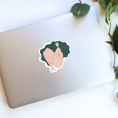 Computador portátil prateado com autocolante e planta ao lado