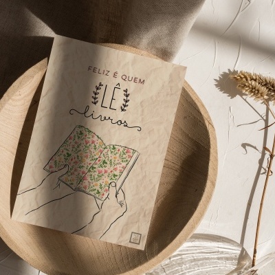 Livro com capa bege clara e ilustração floral numa base de madeira circular junto a ramo seco e fundo branco.