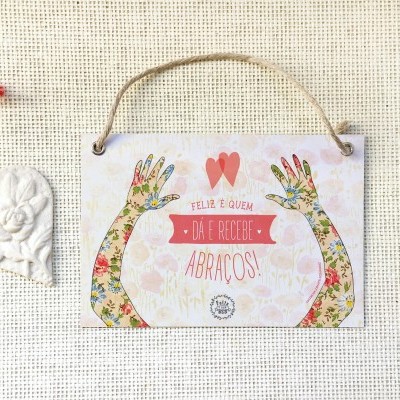 Placa decorativa pendurada com texto e coração em tecido ao lado.