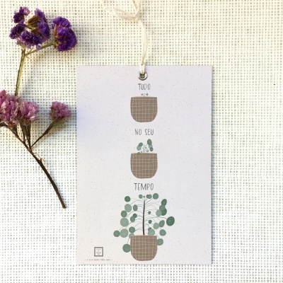 Cartão com ilustração de vasos de plantas e texto pendurado sobre tecido cru com flores secas ao lado