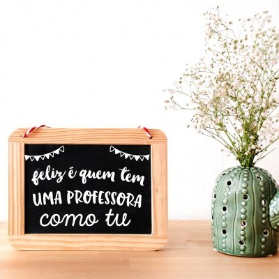 Placa decorativa com texto para professora e vaso de cerâmica em forma de cacto sobre mesa