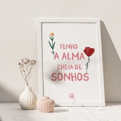 Quadro branco com moldura branca e texto em português com imagens de flores ao lado de peças cerâmicas sobre mesa branca