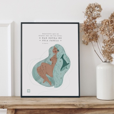 Quadro com ilustração de mulher e texto em português, apoiado em madeira ao lado de vaso com flores secas