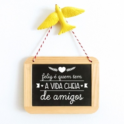 Placa decorativa com texto em fundo negro e pássaro amarelo pendurado