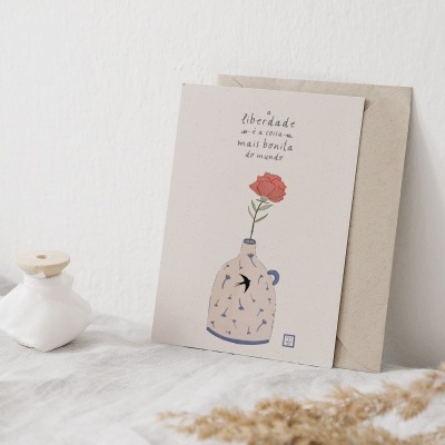 Cartão decorativo com ilustração de vaso e flor vermelha sobre tecido branco