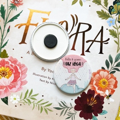 Livro FO'RA com capa floral e dois ímanes redondos, um com ponto preto e outro com figura de yoga e texto em português.