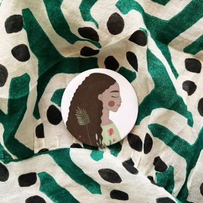 Botão com ilustração de mulher sobre tecido com padrão verde e preto
