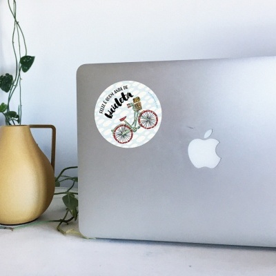 Portátil prateado com autocolante de bicicleta e vaso amarelo com planta