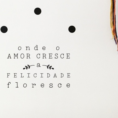 Texto decorativo em português com três pontos pretos e fios coloridos pendurados