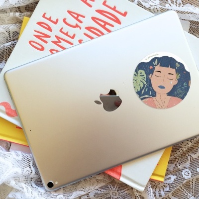 Tablet prateado com autocolante de mulher e livros sobre pano de renda branco