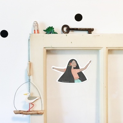 Porta branca com autocolante de personagem feminina, suspensão decorativa de madeira e arame, dinossauro verde e chave antiga em cima