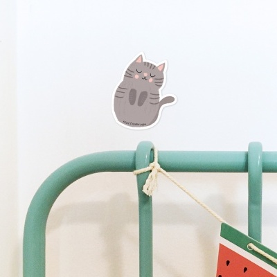 Estrutura metálica verde com adesivo de gato cinzento e placa em forma de melancia pendurada