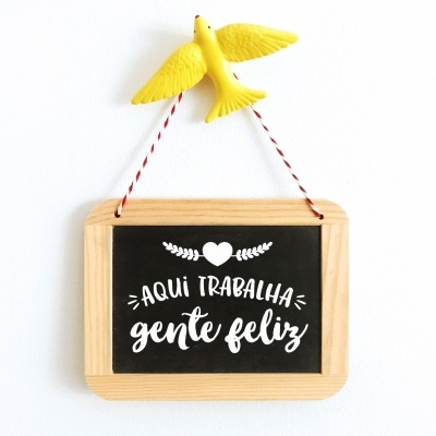 Placa decorativa com texto em português pendurada e pássaro amarelo