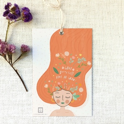 Cartão decorativo com ilustração feminina e flores secas sobre tecido cru.