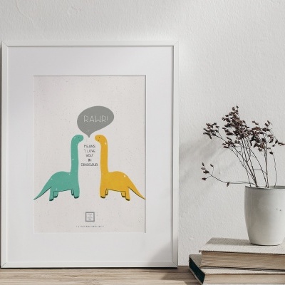 Poster com dinossauros coloridos numa moldura branca sobre uma mesa de madeira com um vaso branco e livros