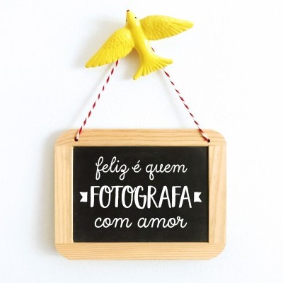 Quadro negro com moldura de madeira e pássaro amarelo pendurado na parede