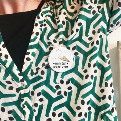 Blusa com padrão geométrico verde e branco e crachá redondo com texto em português