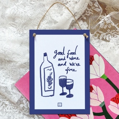 Placa decorativa com ilustração e texto sobre fundo de tecido rendado e cartão com flores
