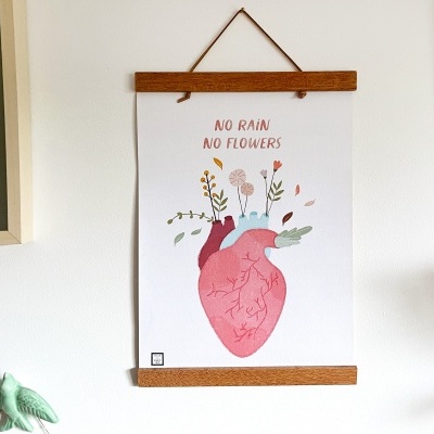 Pôster branco com ilustração de coração anatômico rosa com flores e texto 'NO RAIN NO FLOWERS', pendurado na parede