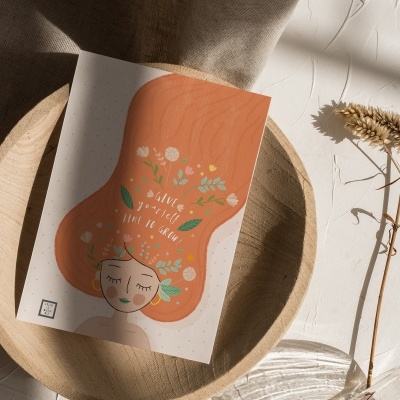 Cartão ilustrativo com cabeça e cabelo laranja sobre prato de madeira e superfície branca