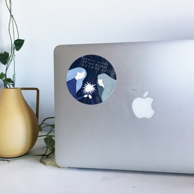 Computador portátil prateado Apple com autocolante azul e vaso amarelo com planta