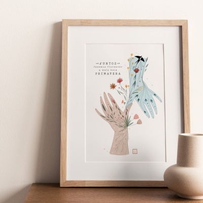 Quadro decorativo com ilustração de mãos e flores, moldura de madeira clara, sobre mesa com vasos decorativos.
