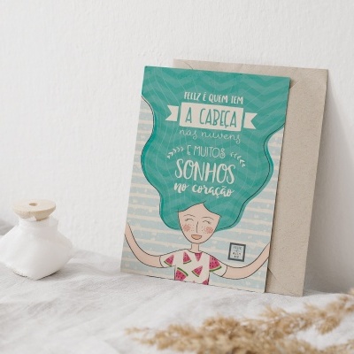 Cartão decorativo com desenho e texto em português colocado contra parede branca