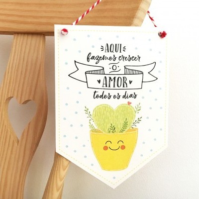 Plaquinha decorativa com texto e desenho pendurada numa cadeira de madeira