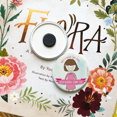 Livro infantil 'Flora' com capa florida e dois bottons redondos em cima.