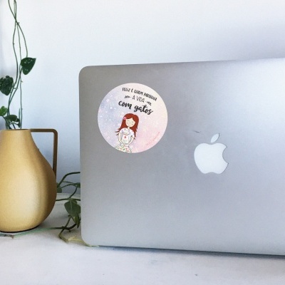 Computador portátil Apple prateado com autocolante e vaso amarelo com planta