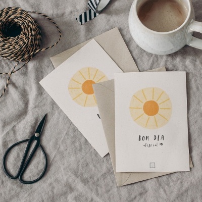 Cartões de papel com desenhos de sol e texto, tesouras, cordas e caneca sobre tecido cinza