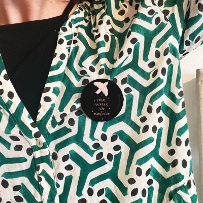 Blusa padrão geométrico verde e preto com broche preto e laço cor-de-rosa