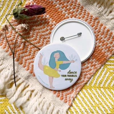 Dois bottons redondos sobre tapete tecido colorido com fio laranja, branco e amarelo