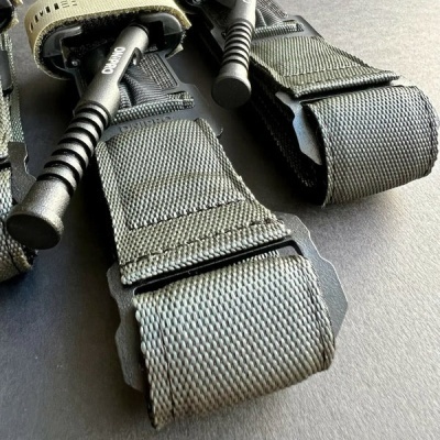 Duas ligaduras táticas verdes com pinos de extracção ON/OFF numa superfície cinza