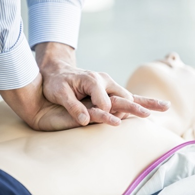 Pessoa a fazer compressões torácicas num manequim de reanimação em treino