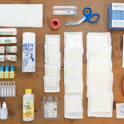 Kit de primeiros socorros com diversos produtos médicos sobre superfície de madeira.