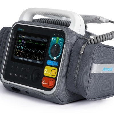 Desfibrilhador portátil com ecrã a mostrar sinais vitais e caixa cinzenta com bolsa lateral