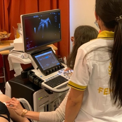 Equipamento de ecografia com profissional de saúde e paciente num consultório