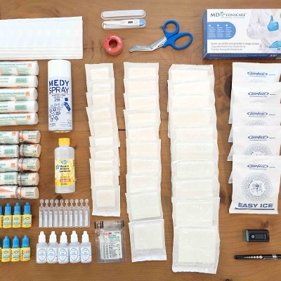 Produtos de primeiros socorros variados organizados numa mesa de madeira.