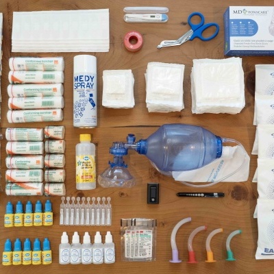 Conjunto de equipamentos médicos e primeiros socorros organizados sobre uma mesa de madeira