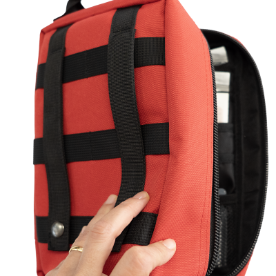 Mochila ou bolsa vermelha com alças pretas, parcialmente aberta e segurada por uma mão