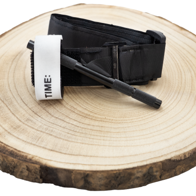 Torniquete preto com fecho de velcro branco com texto TIME: e dispositivo preto sobre disco de madeira