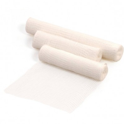 Rolos de gaze médica branca desenrolada sobre fundo branco.