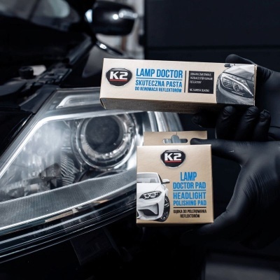 Produto K2 para tratamento de faróis com pasta e esponja de polimento junto a farol de carro