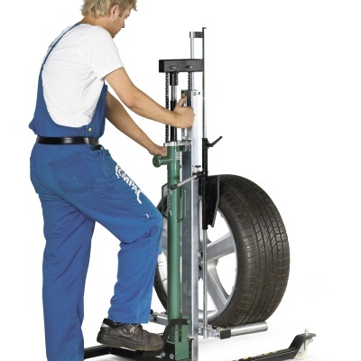 Homem a operar máquina de montagem de pneus com pneu e jante